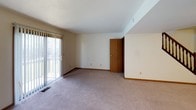 This three-floor home offers a practical and well-organized layout designed to maximize both living space and storage throughout each level. The main living area is generously sized, carpeted, and filled with natural light from a large sliding glass door that opens to an outdoor balcony, creating a bright and open atmosphere. Adjacent to the living space is a functional kitchen equipped with white cabinetry trimmed in warm wood tones, ample counter space, a stainless steel sink, and a white electric range with overhead ventilation.

The upper level houses the bedrooms, each finished with neutral carpet and fitted with wood-paneled doors. One bedroom features a double closet setup with bifold doors and a window for natural light, while additional bedrooms offer individual closets and window access. Two bathrooms serve the upper floors — one featuring a full tub-shower combination and a vanity with under-sink storage, and another compact bath with a pedestal sink, mirror, and shower area.

The lower level provides additional versatile living space with carpet, a textured ceiling, built-in shelving, and windows that allow in natural light. A dedicated utility and laundry room on this level includes an in-unit washer and dryer alongside a water heater, completing the home's practical amenities.