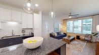 Located at 555 Bishop Gate Lane in Jacksonville, FL, this single-story residence offers a thoughtfully designed open-concept floor plan with contemporary finishes and a warm, inviting ambiance. The living area features light hardwood-style flooring, a ceiling fan, and large windows that flood the space with natural light while offering pleasant outdoor views. Coastal-inspired décor and neutral tones contribute to a relaxed yet refined atmosphere throughout.

The kitchen is a standout feature, showcasing a striking two-tone cabinetry design with crisp white upper cabinets and deep navy lower cabinets, complemented by dark granite countertops and a classic subway tile backsplash. A generously sized island provides additional prep and seating space, while stainless steel appliances and globe pendant lighting complete the polished look. The kitchen flows seamlessly into the living area, making it ideal for everyday living and entertaining.

The bedrooms are carpeted and comfortably sized, each offering natural light through well-dressed windows with blinds and ceiling fans. The bathroom is clean and functional, featuring a full tub-shower combination with white tile surround. Throughout the residence, the consistent use of quality materials, cohesive color palettes, and thoughtful design details create a comfortable and stylish living environment.