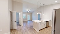 Located at 13120 Royal Palm Way in Farragut, TN, this single-story, three-bedroom, two-bathroom home offers a well-designed open-concept layout with modern finishes throughout. The kitchen is a standout feature, showcasing white shaker cabinetry, stainless steel appliances including a refrigerator, range, and microwave, a crisp white countertop island with a built-in sink, and elegant pendant lighting overhead. Light wood-style flooring extends through the main living areas, complementing the airy, neutral color palette. The living area benefits from vaulted ceilings and a ceiling fan, creating a bright and comfortable atmosphere with natural light filtering in through multiple windows. The spacious primary bedroom features plush carpeting, a ceiling fan, a walk-in closet with built-in shelving, and direct access to a private en-suite bathroom with a glass-enclosed shower and white vanity cabinetry. Additional bedrooms are generously sized with carpeting and ceiling fans. The second bathroom offers a full tub-shower combo with subway tile surround and hardwood-style flooring. A dedicated laundry room includes a full-size washer and dryer. This home combines practical functionality with clean, contemporary design in a desirable Farragut location.