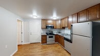 Located at 401 E Magnesium Rd in Spokane, WA, this one-bedroom, one-bathroom unit offers a practical and comfortable layout across a single floor. The open-concept kitchen and living area serves as the heart of the home, where warm hardwood-style flooring flows seamlessly throughout. The kitchen is well-appointed with rich wood cabinetry, granite-style countertops, and a full suite of stainless steel appliances including a gas range, microwave, refrigerator, and dishwasher. The spacious living area is bright and airy, benefiting from a ceiling fan and a sliding glass door fitted with vertical blinds that opens to a private balcony with views of surrounding greenery. The bedroom is a cozy retreat with a window framing lush outdoor views, a baseboard heating unit, and ample closet space. The bathroom features a walk-in shower, wood-tone vanity with granite-style countertop, and hardwood-style flooring consistent with the rest of the unit. A dedicated utility room rounds out the floor plan. Baseboard heating is present throughout, ensuring year-round comfort in this efficiently designed Spokane residence.