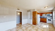 Located at 1514 Nunneley Pl in Wichita Falls, TX, this single-story, 2-bedroom, 2-bathroom home offers a practical and well-organized layout. The interior features a neutral color palette with light gray walls and white trim throughout, complemented by textured ceilings that add character to every room.

The kitchen is efficiently designed with warm honey-toned wood cabinetry extending to the upper walls for ample storage, solid countertops, a built-in pantry cabinet, and a full suite of white appliances including a refrigerator, range, microwave, and dishwasher. Large-format tile flooring runs through the kitchen and main living areas, providing durability and easy maintenance.

The primary bedroom is a comfortable, well-sized room featuring wood-look laminate flooring, a ceiling fan with light fixture, a window for natural light, and access to a dedicated closet. The second bedroom also features laminate flooring, natural light from a window, and its own closet. Both bathrooms are functional, with one featuring a full tub-shower combo finished with large-format beige tile surround. The hallway connects the rooms efficiently, and two closets provide additional storage throughout the home.