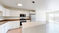 Located at 219 12th St NE in Dilworth, Minnesota, this well-appointed 3-bedroom, 2-bathroom residence offers a comfortable and functional single-floor layout. The open-concept kitchen and living area serves as the heart of the home, with light wood-style flooring that creates a warm, cohesive feel. The kitchen is equipped with white cabinetry, dark wood-toned countertops, stainless steel refrigerator, and matching appliances including an electric range and over-the-range microwave. The living area opens directly to a private balcony through sliding glass doors, offering pleasant outdoor views and natural light. Each bedroom features plush carpeting, ceiling fans with lighting, and baseboard heating. The spacious primary bedroom includes a walk-in closet with wire shelving for ample storage. Secondary bedrooms also offer closet space and ceiling fans. Two full bathrooms serve the residence — one with a walk-in shower and one with a full tub/shower combo — both finished with wood-style vinyl flooring, white vanity cabinetry, and clean, bright fixtures. A dedicated laundry area houses a full-size Whirlpool washer and dryer, adding everyday convenience. Throughout, the residence maintains a clean, neutral palette with white walls and consistent modern finishes.