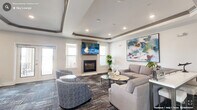 The Watchorn St Sky Lounge in Durham, NC, is a thoughtfully designed communal space that blends contemporary aesthetics with functional versatility. The lounge is organized into distinct yet open zones, creating a seamless flow throughout. Signature tray ceilings with gray-trimmed molding and recessed lighting lend architectural interest and a sense of refined elegance to every area.

The primary living area anchors the space with a built-in fireplace topped by a wall-mounted television, surrounded by plush, neutral-toned sofas and accent chairs arranged around glass-topped coffee tables. Bold abstract artwork adorns the crisp white walls, adding vibrant color and artistic character. Textured, multi-toned carpet throughout provides warmth and a sophisticated visual layer underfoot.

An adjacent wet bar area features dark cabinetry with light countertops, a sink, and a mounted television, making it well-suited for entertaining. Nearby, bistro-style tables and chairs offer intimate seating for small groups. French doors along one wall open to an outdoor terrace, inviting natural light and views of the surrounding area.

The entry corridor features glass-paneled doors, a decorative console, and additional art, offering a welcoming transition into the lounge. Windows positioned throughout ensure the space remains bright, open, and inviting at all times.