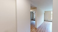 Located at 555 Pacific Ave in Santa Cruz, California, this one-bedroom, one-bathroom unit offers a thoughtfully designed, efficient layout with modern finishes throughout. Warm hardwood-style flooring flows consistently across the entire space, providing a cohesive and inviting atmosphere.

The combined kitchen and living area is a standout feature of the unit. The kitchen is outfitted with a full suite of stainless steel appliances — including a refrigerator, electric range, built-in microwave, and dishwasher — complemented by light wood cabinetry offering ample storage and dark countertops that provide a sleek contrast. Exposed industrial ductwork along the upper walls and ceiling adds a contemporary, loft-inspired character to the space. Track lighting illuminates the kitchen area effectively.

The living room is bright and open, featuring large windows that frame lush outdoor greenery, filling the space with natural light. An exposed duct runs along one wall, continuing the industrial design aesthetic. A door leads directly to an outdoor area, further enhancing the connection to the surroundings.

The bedroom is a calm, well-proportioned room featuring a ceiling fan and a built-in closet. Clean white walls and natural light create a restful environment.

The bathroom is accessed through a distinctive frosted glass door and features a vanity with cabinetry, hardwood-style flooring, and a clean, minimalist design. A hallway connects the rooms efficiently, completing this well-appointed unit.