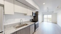 Located at 9275 North 29th Avenue in Phoenix, AZ, this modern one-bedroom, one-bathroom unit offers a thoughtfully designed open-concept layout with contemporary finishes throughout. Light wood-look flooring flows seamlessly across the entire space, enhancing the bright, airy atmosphere created by white walls and recessed lighting.

The kitchen features a galley-style design with dark wood cabinetry contrasted by crisp white upper cabinets, granite-look countertops, and a full suite of stainless steel appliances including a refrigerator, electric range, microwave, and dishwasher. The kitchen opens directly into the living area, which benefits from a ceiling fan and access to a private balcony through sliding glass doors, filling the space with natural light.

The bedroom is a well-proportioned room with a ceiling fan, a window with natural light, and direct access to a spacious walk-in closet equipped with dual hanging rods and shelving. The bathroom echoes the kitchen's design language with matching dark wood cabinetry, a granite-look vanity countertop, a large mirror, and light-filled surroundings. A hallway connects the main living areas efficiently, completing this well-appointed and move-in ready home.