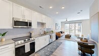 Located at 523 S Madison Ave in Greenwood, Indiana, this thoughtfully designed single-floor residence offers a comfortable and modern living experience. The open-concept layout seamlessly connects the kitchen and living room, creating a bright and functional shared space. The kitchen is well-equipped with crisp white shaker cabinetry extending to the ceiling, stainless steel appliances including a range, microwave, dishwasher, and refrigerator, complemented by neutral quartz-style countertops and a subtle tile backsplash. Light wood-style flooring flows throughout the entire unit, enhancing the cohesive, contemporary aesthetic. The living area is bathed in natural light from a large sliding glass door that opens to an outdoor balcony, with a ceiling fan adding comfort overhead. The bedroom is a calm and spacious retreat, featuring dual windows for natural light, a ceiling fan, and generous proportions for furniture arrangement. The full bathroom includes a tub-shower combination with tile surround, a white vanity, and wood-style flooring that ties into the rest of the unit. Two closets provide ample storage, and a dedicated laundry area adds everyday convenience. Recessed lighting throughout and a neutral color palette give the space a clean, modern character.