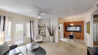 Located in Chandler, Arizona, this single-floor residence offers a thoughtfully arranged 2-bedroom, 2-bathroom layout that maximizes comfort and functionality. The open living area features plush carpeting, a ceiling fan, and built-in shelving niches, with natural light streaming in through sliding glass patio doors. The space flows seamlessly into a dedicated dining area, distinguished by a warm terracotta accent wall, pendant lighting, and an arched passthrough connecting to the kitchen. The galley-style kitchen is well-equipped with light wood cabinetry, dark granite-style countertops, black appliances including a range with built-in microwave, and a window that brings in additional natural light. The primary bedroom is a comfortable retreat featuring a ceiling fan, carpet flooring, a bold blue accent wall, and a window with outdoor views. The second bedroom is equally inviting with soft neutral tones and natural light. A spacious walk-in closet provides generous storage with multiple shelving levels and hanging rods. Both bathrooms are finished with wide vanity mirrors, light wood cabinetry, and dark countertops, with one bathroom featuring a full soaking tub and shower combination. Throughout, the home maintains a warm, neutral palette accented by thoughtful design touches.