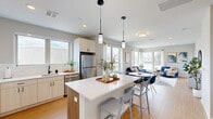 Located at 55 Seely School Dr in Groton, CT, this thoughtfully designed one-bedroom, one-bathroom residence offers a comfortable and modern living experience across a single floor. The open-concept layout seamlessly connects the kitchen, dining area, and living room, creating a bright and airy atmosphere enhanced by large windows that flood the space with natural light and offer pleasant outdoor views.

The kitchen is a standout feature, boasting sleek white upper cabinetry paired with warm wood-toned lower cabinets, crisp white quartz countertops, stainless steel appliances including a refrigerator, dishwasher, and range, and a central island with bar seating illuminated by stylish pendant lights. Light hardwood flooring ties the kitchen and living areas together seamlessly.

The living room is generously proportioned, featuring recessed lighting, large windows with sheer drapes, and direct access to a private balcony. The bedroom offers a cozy retreat with plush carpeting and ample space for a full furniture arrangement. Two closets provide excellent storage throughout the unit.

The bathroom is elegantly finished with large-format marble-look tile flooring, a wood-grain vanity with white countertop, a framed mirror, and a tall linen storage cabinet. Additional conveniences include a dedicated laundry area and a welcoming entrance hallway.