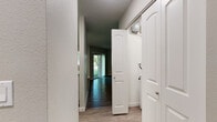 This single-floor residence offers a thoughtfully designed layout with a neutral color palette and modern finishes throughout. The entryway provides immediate access to the main living areas, with wood-look hardwood-style flooring extending through the common spaces, creating a cohesive and contemporary aesthetic.

The open living area features a sliding glass door that invites natural light and offers views of the surrounding greenery, with an additional window further brightening the space. A subtly raised section within the living area adds architectural interest and defined zoning.

The kitchen is outfitted with stainless steel appliances, including an electric range and over-the-range microwave, complemented by white shaker-style cabinetry and light stone countertops. A notable convenience is the dedicated in-unit laundry space, visible directly from the kitchen, accommodating a full-size washer and dryer.

The bedrooms are carpeted for comfort, each featuring ceiling fans with integrated lighting and generous closet storage. One bedroom includes dual closets, offering ample organization options.

The bathroom presents a clean, functional design with a full tub-and-shower combination, neutral gray walls, wood-look flooring, and white cabinetry, finished with brushed nickel hardware throughout.