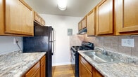 Located at 1293 Bayside Avenue in Woodbridge, VA, this two-bedroom, one-bathroom residence offers a functional and well-organized single-floor layout. The galley-style kitchen is efficiently designed with warm wood cabinetry, granite-look countertops, a tile backsplash, and black appliances including a gas range and full-size refrigerator, all set over hardwood-style flooring. The spacious living area is carpeted in neutral tones and features large sliding glass doors dressed with vertical blinds, opening to a private balcony that brings in natural light and outdoor views. A ceiling fan adds comfort to this open living space. The generously sized primary bedroom offers ample room and carpet flooring, while the second bedroom is equally well-proportioned with soft carpet, neutral gray walls, and a window overlooking greenery. Both rooms provide a calm, understated atmosphere. The bathroom is clean and straightforward, featuring a full soaking tub with tiled surround and a vanity with storage. A dedicated closet and hallway round out the layout, contributing to the overall practicality of this Woodbridge residence.