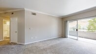 This single-floor residence offers 2 bedrooms and 2 bathrooms across a thoughtfully designed layout. The open living room is finished with soft wall-to-wall carpeting, crown molding, and a textured ceiling, creating a warm and welcoming atmosphere. Large sliding glass doors lead to a private balcony, filling the space with natural light and providing outdoor views. The kitchen is a functional galley-style design featuring dark wood cabinetry, light quartz countertops, wood-look vinyl flooring, and stainless steel appliances including a refrigerator, range, microwave, and dishwasher. A pass-through connects the kitchen to the living area for easy interaction between spaces. The primary bedroom is generously sized with plush carpeting, a window with blinds for natural light, and access to a dedicated walk-in closet with built-in shelving. The second bedroom mirrors similar finishes and comfort. Both bathrooms are well-appointed; one features a soaking tub with tiled surround and wood-look flooring. A hallway connects the private areas of the home, and a dedicated closet provides additional storage. Throughout, neutral tones and consistent finishes create a cohesive and move-in-ready living environment.