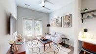 Located at 1417 Hampton Avenue Ext in Greenville, SC, this 1-bedroom, 1-bathroom unit offers a smartly designed single-floor layout with modern finishes throughout. The living room is a standout space, boasting notably high ceilings, a ceiling fan, and French doors that flood the room with natural light while offering views of the greenery outside. Durable wood-look flooring and neutral walls create a clean, contemporary backdrop. A built-in desk nook adds functional versatility to the living area.

The kitchen is outfitted with stainless steel appliances, including a range, microwave, and dishwasher, complemented by crisp white countertops, grey shaker-style cabinetry, and open shelving for added storage and display.

The spacious primary bedroom features plush carpet, high ceilings, a large window for natural light, and direct access to a dedicated closet with built-in shelving. The bathroom is neatly appointed with a wood-toned vanity with drawers, a mirror, and light tile flooring, conveying a clean and functional design. A glass-enclosed shower is also visible in the layout. A separate closet provides additional storage. The overall ambiance of the unit is modern, bright, and efficiently organized.