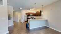 Located at 644 N Main St in the heart of Greenville, SC, this one-bedroom, one-bathroom unit offers a thoughtfully designed single-floor layout that maximizes functionality and comfort. The open-concept kitchen and living area serves as the centerpiece of the space, featuring rich dark cabinetwood cabinetry, granite countertops, and a full suite of stainless steel appliances including a refrigerator, range, and microwave. A peninsula with pendant lighting creates a natural division between the kitchen and living area while offering additional counter seating. Track lighting overhead enhances the kitchen's modern aesthetic. The living area is finished with durable hardwood-style flooring and benefits from a large window that invites abundant natural light and outdoor views, complemented by a ceiling fan for year-round comfort. The bedroom is carpeted for warmth, featuring a double-door closet and its own ceiling fan. Upper transom windows bring in additional light while maintaining privacy. The bathroom is clean and functional, offering a full tub-shower combination with tiled surround, granite-topped vanity with dark cabinetry, and wood-style flooring that ties the space together cohesively. Neutral tones throughout create a calm, versatile atmosphere suited for a range of styles.