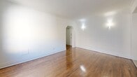 Located at 1660 Bathurst Street in Toronto's Forest Hill South neighbourhood, this one-bedroom, one-bathroom unit offers a well-organized layout across a single floor. Warm hardwood flooring runs throughout the main living areas, lending a classic and inviting character to the space.

The living room is generously proportioned, featuring crown moulding, crisp white walls, and a large window fitted with a radiator beneath it, providing ample natural light and comfortable heating. An elegant arched doorway connects the living room to the hallway, adding a touch of architectural charm.

The galley-style kitchen is efficiently designed with white cabinetry, tile backsplash, light tile flooring, and stainless steel appliances including a full-size refrigerator, dishwasher, and stove. A window at the end of the kitchen brings in natural light and ventilation.

The bedroom is a comfortable size, with hardwood floors, white walls, and two interior doors providing access to additional storage or closet space.

The bathroom features floor-to-ceiling neutral tile surrounding a full soaking tub and shower, complemented by a window for natural ventilation. A central hallway connects all rooms, ensuring a functional and straightforward flow throughout the unit.