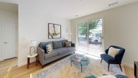 This thoughtfully designed two-bedroom, two-bathroom residence offers a clean, modern aesthetic throughout its single-floor layout. Light wood flooring flows consistently across the main living areas, anchoring a bright and cohesive interior palette of soft whites and warm neutrals.

The living room serves as a welcoming central hub, featuring large sliding glass doors that open to a private balcony overlooking mature trees, allowing generous natural light to fill the space. The kitchen is outfitted with sleek charcoal-gray cabinetry, white quartz countertops, a subway tile backsplash, and a full suite of stainless steel appliances, including a gas range and built-in microwave. The entry opens directly into this well-appointed kitchen area.

Both bedrooms are comfortably sized with large windows framing leafy outdoor views. Each room features closet space and is served by its own dedicated bathroom. One bathroom includes a tub-shower combination with tile surround, while the second offers a walk-in shower, both finished with white cabinetry and clean, minimal fixtures.

A versatile bonus room, ideal as a home office or den, features a sizable window and additional storage. The overall ambiance is modern, light-filled, and welcoming.