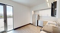 Located at 224 20th St in the heart of Miami Beach, FL, this three-bedroom, one-bathroom unit offers a modern, clean aesthetic throughout. The layout is contained on a single floor, with a bright, wide hallway connecting the rooms and providing a sense of openness despite the compact footprint.

The kitchen is a standout feature, equipped with stainless steel appliances including a full-size refrigerator, dishwasher, and range. White upper cabinetry is paired with warm wood-toned lower cabinets and light countertops, accented by sleek linear LED lighting that adds a contemporary touch.

The three bedrooms are finished with light wood-look flooring and crisp white walls. The primary bedroom includes a built-in closet with shelving, offering practical storage. Recessed and linear lighting fixtures illuminate each room evenly.

The bathroom is clean and well-appointed, featuring a subway-tiled tub and shower surround, a wood-vanity with a white stone countertop, an undermount sink, and a large frameless mirror.

Throughout, dark baseboards contrast neatly against the light flooring, reinforcing the modern design language. The unit also benefits from elevated views of the Miami Beach skyline and surrounding neighborhood, visible from the building's upper level outdoor area, bringing the vibrant South Beach surroundings right to the doorstep.