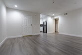 Located at 5623 Carlton Way in the heart of Hollywood, Los Angeles, this single-floor unit offers a clean, modern aesthetic throughout. Light wood-style flooring runs continuously across the living areas, complemented by crisp white walls and recessed lighting that create a bright, airy atmosphere.

The living room serves as the central gathering space, featuring a classic fireplace with a sleek black surround and a window fitted with vertical blinds that allow natural light to filter in. An adjacent area connects seamlessly to the entryway, which opens directly to the kitchen.

The kitchen is well-appointed with white shaker-style cabinetry, quartz countertops, a subway-style mosaic tile backsplash, and a full suite of stainless steel appliances including a gas range, built-in microwave, dishwasher, and refrigerator. The layout maximizes functionality while maintaining a polished look.

The bedrooms are generously sized with neutral tones and ample natural light. One bedroom features a sliding glass door with access to a private balcony, while another offers dual windows overlooking the exterior. The bathrooms are finished with large-format beige tile surrounds in the tub-shower combinations, paired with brushed nickel fixtures for a refined, contemporary feel throughout.