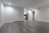 Located at 5623 Carlton Way in the heart of Hollywood, Los Angeles, this single-floor unit offers a clean, modern aesthetic throughout. Light wood-style flooring runs continuously across the living areas, complemented by crisp white walls and recessed lighting that create a bright, airy atmosphere.

The living room serves as the central gathering space, featuring a classic fireplace with a sleek black surround and a window fitted with vertical blinds that allow natural light to filter in. An adjacent area connects seamlessly to the entryway, which opens directly to the kitchen.

The kitchen is well-appointed with white shaker-style cabinetry, quartz countertops, a subway-style mosaic tile backsplash, and a full suite of stainless steel appliances including a gas range, built-in microwave, dishwasher, and refrigerator. The layout maximizes functionality while maintaining a polished look.

The bedrooms are generously sized with neutral tones and ample natural light. One bedroom features a sliding glass door with access to a private balcony, while another offers dual windows overlooking the exterior. The bathrooms are finished with large-format beige tile surrounds in the tub-shower combinations, paired with brushed nickel fixtures for a refined, contemporary feel throughout.