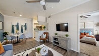 This single-floor residence offers a thoughtfully designed layout that balances functionality with modern style. The open-concept living area serves as the heart of the home, featuring durable wood-look flooring, crown molding, and a ceiling fan overhead. Large windows allow natural light to fill the space, creating a bright and welcoming ambiance. The living area flows seamlessly into the kitchen, which is separated by a peninsula with granite countertops — ideal for casual dining or entertaining. The galley-style kitchen is well-equipped with stainless steel appliances, including a refrigerator, range, microwave, and dishwasher, all complemented by gray shaker-style cabinetry and additional granite countertop workspace. The bedroom is generously proportioned, featuring plush carpet flooring, a ceiling fan, and multiple windows that bring in ample natural light. A bold accent wall adds a warm, distinctive character to the room. The full bathroom continues the granite countertop theme, paired with white cabinetry, wood-look flooring, and a full soaking tub with a tiled surround. Throughout the residence, a cohesive neutral palette with warm accent tones creates a comfortable and inviting atmosphere.
