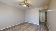 Located at 225 N Gilbert Rd in Mesa, AZ, this single-story, one-bedroom, two-bathroom unit offers a well-designed layout with modern updates throughout. Durable wood-look laminate flooring runs consistently across every room, creating a cohesive and easy-to-maintain interior.

The kitchen is a standout feature, outfitted with grey shaker-style cabinetry, white quartz countertops, a classic subway tile backsplash, and a full suite of stainless steel appliances including a refrigerator, electric range, over-the-range microwave, and dishwasher. The galley-style layout maximizes efficiency within the space.

The bedroom is a comfortable size, featuring a ceiling fan with light fixture, a large window with vertical blinds that allows ample natural light, and convenient access to a dedicated closet. The neutral grey-toned walls lend a clean, modern aesthetic.

Both bathrooms are well-appointed. One features an extended grey vanity with white countertop, a large mirror with overhead lighting, and wood-look flooring. A full tub-shower combo with white tile surround completes the bathroom amenities.

Hallways connect the rooms efficiently, and ceiling fans in the main living areas provide year-round comfort. The overall design is clean, contemporary, and move-in ready.