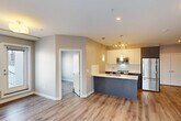 Located at 11303 105 Avenue NW in Edmonton, Alberta, this well-designed 2-bedroom, 1-bathroom unit offers a thoughtfully planned open-concept layout across a single floor. Light-toned luxury vinyl plank flooring flows throughout, unifying the living, dining, and kitchen areas into a cohesive and functional space.

The kitchen is a standout feature, showcasing bold two-tone cabinetry in deep blue and white with upper white cabinets, a crisp white countertop island with an undermount sink, pendant lighting, and a full suite of stainless steel appliances including a refrigerator, stove, and built-in microwave. The open-concept design connects the kitchen seamlessly to the living area, which benefits from large windows that draw in natural light and offer views of the surrounding Edmonton cityscape.

Both bedrooms are well-proportioned and finished with the same warm hardwood-style flooring. Each room features windows with urban views, and the primary bedroom includes a dedicated closet with sliding doors. A total of three closets provide ample storage throughout the unit.

The bathroom features large-format tile flooring, a dark wood vanity with white countertop, an illuminated LED mirror, and a clean, modern aesthetic. An in-unit laundry area adds everyday convenience to this move-in-ready space.