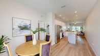 Located at 3905 Bahama Dr in Wildwood, Florida, this well-appointed single-story home offers three bedrooms, two bathrooms, and a thoughtfully designed open-concept floor plan. The bright living room features light wood-style flooring, a ceiling fan, and sliding glass doors that invite natural light and outdoor views. Adjacent to the living area, the dining space benefits from large windows and a clean, airy aesthetic with vaulted ceiling accents. The kitchen is outfitted with crisp white shaker cabinetry, granite-style countertops, a subway tile backsplash, and stainless steel appliances, offering both style and functionality. The primary bedroom is a comfortable retreat with its own walk-in closet equipped with wire shelving for ample storage. Additional bedrooms feature windows with natural light and ceiling fans. The bathrooms are finished with granite vanity tops, white cabinetry, wood-look flooring, and a glass-enclosed walk-in shower. A dedicated laundry room houses a full-size washer and dryer. The home sits within a community that includes a pool area and landscaped common grounds, visible from the exterior. Light neutral tones and consistent wood-look flooring throughout give the home a cohesive, modern feel.