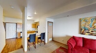 This two-floor residential space offers a well-organized and functional layout designed for comfortable everyday living. The main living area is open and inviting, featuring plush carpeting, a large sliding glass door with vertical blinds that allows generous natural light to flow in, and ample room for seating and relaxation. A breakfast bar with bar seating connects the living space to the kitchen, creating a seamless open-concept flow. The kitchen is equipped with warm honey-toned wood cabinetry, a double-basin sink, electric range with over-the-range microwave, a full-size refrigerator, and a dishwasher, all set atop easy-care hardwood-style flooring. The bedrooms are carpeted and comfortable, each featuring ceiling fans with lighting fixtures and windows that bring in natural light. The space includes two full bathrooms, each appointed with a shower-tub combination and vanity. Throughout the home, a consistent neutral color palette on the walls creates a clean, welcoming ambiance. The overall layout is practical and well-proportioned, offering distinct spaces for living, dining, cooking, and sleeping across its two floors.