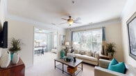 This thoughtfully designed single-floor residence in Durham, NC, offers a welcoming and cohesive living experience highlighted by an abundance of natural light and contemporary styling throughout. The spacious living room serves as the heart of the home, featuring plush carpet, crown molding, a ceiling fan, and large windows with blinds that allow generous sunlight to pour in. The open layout connects seamlessly to a sunlit sitting or dining area, creating an ideal flow for everyday living and entertaining. A cozy seating nook with a statement cityscape artwork adds a refined touch to the living space. The kitchen is equipped with granite-style countertops, hardwood flooring, a breakfast bar, and includes an in-unit laundry area for added convenience. Both bedrooms offer a serene retreat, each featuring a bold teal accent wall that adds a vibrant pop of color, complemented by ceiling fans and ample natural light. The two bathrooms are finished with rich granite-topped vanities, white cabinetry, and warm hardwood floors, with one featuring a full soaking tub. Located at 600 Stone Lion Dr, this residence combines functional design with stylish details throughout.