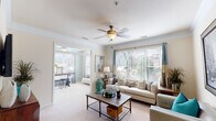 This thoughtfully designed single-floor residence in Durham, NC, offers a welcoming and cohesive living experience highlighted by an abundance of natural light and contemporary styling throughout. The spacious living room serves as the heart of the home, featuring plush carpet, crown molding, a ceiling fan, and large windows with blinds that allow generous sunlight to pour in. The open layout connects seamlessly to a sunlit sitting or dining area, creating an ideal flow for everyday living and entertaining. A cozy seating nook with a statement cityscape artwork adds a refined touch to the living space. The kitchen is equipped with granite-style countertops, hardwood flooring, a breakfast bar, and includes an in-unit laundry area for added convenience. Both bedrooms offer a serene retreat, each featuring a bold teal accent wall that adds a vibrant pop of color, complemented by ceiling fans and ample natural light. The two bathrooms are finished with rich granite-topped vanities, white cabinetry, and warm hardwood floors, with one featuring a full soaking tub. Located at 600 Stone Lion Dr, this residence combines functional design with stylish details throughout.