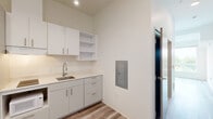 Located at 5460 N Interstate Ave in Portland, Oregon, this efficiently designed one-bedroom, one-bathroom unit offers a thoughtful layout across a single floor. The interior features light wood-look luxury vinyl plank flooring throughout, complementing the clean, neutral color palette of the crisp white walls.

The kitchen is smartly organized with white flat-front cabinetry, open shelving, a stainless steel sink with a contemporary faucet, a built-in electric cooktop, and ample counter space finished in white. A full-size refrigerator, microwave, and recessed lighting complete the functional kitchen setup. An electrical panel is conveniently recessed into the wall nearby.

The spacious bedroom is the highlight of the unit, featuring a ceiling fan and a large set of windows that flood the room with natural light and frame views of the surrounding greenery and a distinctive historic water tower — a charming Portland landmark.

The bathroom maintains the same clean, modern aesthetic with wood-look flooring, a white vanity with under-cabinet storage, a toilet, and a clothing rod for hanging storage, keeping the space practical and uncluttered.

Recessed lighting throughout the unit adds to the bright, airy ambiance, making this a well-appointed and efficiently designed living space in North Portland.