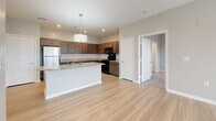 Located at 5636 Old Hickory Blvd in Nashville, TN, this two-bedroom, two-bathroom single-floor residence offers a well-organized layout with a clean, modern aesthetic throughout. The open-concept living and kitchen area features light hardwood-style flooring that runs seamlessly through the main living spaces. The kitchen is equipped with rich dark wood cabinetry, granite countertops, black appliances including a range and built-in microwave, and a peninsula with pendant lighting — providing both functionality and a central gathering point. The living area is bright and airy, with large windows and a glass door that invite natural light and offer outdoor views of the surrounding greenery. Both bedrooms are carpeted and finished with neutral-toned walls, offering a comfortable and quiet retreat. Each room benefits from natural light through sizable windows fitted with blinds. The two bathrooms mirror the kitchen's design language, featuring granite-topped dark wood vanities, light wood-style tile flooring, and a tub-shower combination. Two closets provide convenient storage. The overall palette of soft grays and warm wood tones lends the space a cohesive, contemporary feel well-suited to comfortable living in the Nashville area.