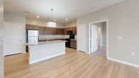 Located at 5636 Old Hickory Blvd in Nashville, TN, this two-bedroom, two-bathroom single-floor residence offers a well-organized layout with a clean, modern aesthetic throughout. The open-concept living and kitchen area features light hardwood-style flooring that runs seamlessly through the main living spaces. The kitchen is equipped with rich dark wood cabinetry, granite countertops, black appliances including a range and built-in microwave, and a peninsula with pendant lighting — providing both functionality and a central gathering point. The living area is bright and airy, with large windows and a glass door that invite natural light and offer outdoor views of the surrounding greenery. Both bedrooms are carpeted and finished with neutral-toned walls, offering a comfortable and quiet retreat. Each room benefits from natural light through sizable windows fitted with blinds. The two bathrooms mirror the kitchen's design language, featuring granite-topped dark wood vanities, light wood-style tile flooring, and a tub-shower combination. Two closets provide convenient storage. The overall palette of soft grays and warm wood tones lends the space a cohesive, contemporary feel well-suited to comfortable living in the Nashville area.