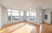 This thoughtfully designed single-floor space combines contemporary style with an abundance of natural light. The open-plan kitchen and living area serves as the heart of the home, anchored by a central island with a sleek grey quartz countertop on casters. The kitchen is outfitted with white shaker cabinetry, grey tile backsplash, stainless steel appliances including a gas range and built-in microwave, and generous storage throughout. A striking skylight directly above the kitchen floods the space with overhead natural light, complemented by a track lighting system throughout.

The adjacent living area is expansive and sun-drenched, featuring warm hardwood flooring that runs seamlessly through the main living spaces. Floor-to-ceiling windows wrap around the room, offering panoramic outdoor views and direct access to a private balcony, creating a strong connection between interior and exterior living.

The bedrooms are comfortably sized with clean white walls and continued hardwood flooring. The bathrooms feature dark slate tile flooring, white vanities with grey countertops, and clean modern fixtures. One bathroom includes a glass-enclosed shower stall, while another is accessible off the hallway. Throughout, the neutral palette, clean lines, and abundant natural light create a bright, airy, and modern ambiance.