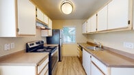 This single-floor residence offers a functional and comfortable layout designed to maximize livability. The living room serves as a central gathering space, highlighted by a classic fireplace with a white mantle surround, neutral carpet flooring, and a door that opens to a private balcony, allowing natural light to fill the room. Adjacent to the living area, the galley-style kitchen is efficiently organized with white cabinetry lining both walls, laminate wood flooring, and stainless steel appliances including an electric range and refrigerator. A window above the sink draws in natural light and provides a view of the surrounding greenery. The bedrooms are generously proportioned, each featuring plush carpet, soft neutral walls, and sliding-door closets with built-in shelving for ample storage. A textured ceiling hallway connects the main living spaces, adding architectural character. The bathroom is finished with wood-look tile flooring, a wide vanity with a single basin, extended countertop space, and dual wall mirrors illuminated by a lighted fixture. Throughout the residence, warm beige tones and consistent finishes create a cohesive and inviting ambiance well-suited for everyday living.