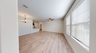 This single-story space offers a well-organized layout with a thoughtful blend of functional and comfortable living areas. The open living and dining area forms the heart of the home, finished with light-toned hardwood-style flooring that extends throughout most of the space. A ceiling fan overhead and a decorative chandelier add character, while large windows fitted with blinds allow ample natural light to fill the room.

The galley-style kitchen is equipped with dark espresso cabinetry, granite-look countertops, and stainless steel appliances including an electric range, microwave, refrigerator, and dishwasher. An arched passageway connects the kitchen to adjacent areas, lending an architectural detail that enhances the overall design. A pantry or utility door provides additional storage directly off the kitchen.

A dedicated mudroom near the garage entry features a built-in bench and wall hooks, offering a practical drop zone. The bathroom includes a dark vanity with granite countertop, wood-style flooring, and a tiled shower area. A walk-in closet with built-in shelving and a hanging rod provides generous storage. The attached garage features a concrete floor and automatic door opener, completing this efficiently designed space.