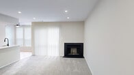 This thoughtfully designed one-bedroom, one-bathroom residence offers a comfortable and functional layout across a single floor. The living room serves as the heart of the home, featuring plush carpeting, recessed lighting, and a sleek black fireplace framed by large sliding doors dressed in vertical blinds that invite natural light and provide outdoor access. The galley-style kitchen is a standout, outfitted with crisp white cabinetry, quartz countertops with a subtle veining pattern, a subway tile backsplash, a matte black faucet, and stainless steel appliances including a refrigerator and range. Light hardwood flooring runs throughout the kitchen and hallway, creating a warm contrast to the carpeted living and sleeping areas. The bedroom is a quiet, well-lit retreat with soft carpet, recessed lighting, and a double window fitted with blinds for natural light and privacy. Two closets provide ample storage throughout the unit. The bathroom is elegantly finished with large-format marble-look tile surrounding the tub and shower, a white vanity with a matching countertop, a black-framed mirror, and hardwood flooring. A dedicated laundry area rounds out this efficiently organized and stylishly updated residence.