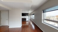 Located at 1954 Jackson Street in Dallas's Uptown neighborhood, this single-floor unit offers a well-designed layout with a modern aesthetic defined by rich, dark hardwood flooring that runs continuously throughout the main living areas and bedroom. The open living space is a standout feature, boasting a row of wide horizontal windows along multiple walls that frame sweeping views of the Dallas skyline and surrounding urban landscape, flooding the interior with abundant natural light.

The kitchen is outfitted with dark espresso cabinetry extending to the ceiling, contrasted by light countertops and a clean white backsplash. Stainless steel appliances—including a refrigerator with ice dispenser, range, built-in microwave, and dishwasher—complete the functional and contemporary workspace.

The bedroom continues the hardwood flooring theme and includes a ceiling fan with integrated lighting, as well as a dedicated closet area. The bathroom features a combination tub and shower with white tile surround, wood-look tile flooring, and a floating dark vanity with a white countertop, maintaining the unit's consistent modern palette.

Neutral gray walls and tray ceiling details in the living area contribute to a clean, contemporary ambiance throughout, making this an attractive urban residence in the heart of Dallas.