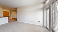 Located at 1705 Dock St, Unit 252 in Tacoma, WA, this 2-bedroom, 1-bathroom residence offers a well-organized single-level layout. The open-concept kitchen and living area form the heart of the home, with the kitchen featuring warm maple cabinetry, dark countertops, a stainless steel appliance suite including a refrigerator, range, and microwave, plus a peninsula with a double sink and a built-in pantry for added storage. Hardwood-style flooring runs throughout the kitchen, while plush carpet covers the spacious living area, which connects seamlessly to a private balcony through large windows that invite generous natural light. Both bedrooms are carpeted and generously sized, each showcasing floor-to-ceiling windows fitted with blinds that frame views of the surrounding neighborhood. The full bathroom includes a soaking tub and shower combination, a warm wood vanity with ample storage, and wood-look tile flooring. Additional conveniences include a dedicated laundry area and three closets distributed throughout the unit, providing practical storage solutions. The hallway connects all spaces efficiently, contributing to a clean, functional flow throughout the residence.