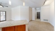 Located at 1 Old Fairway Rd in Huntsville, Alabama, this one-bedroom, one-bathroom residence offers a thoughtfully designed single-level layout. The open-concept kitchen is a standout feature, equipped with warm honey-toned cabinetry, granite countertops, a central island with additional storage, and a full suite of stainless steel appliances including a refrigerator, range, built-in microwave, and dishwasher. Track lighting and elegant pendant lights illuminate the space, while tile flooring grounds the kitchen area. The living area flows naturally from the kitchen, featuring plush carpeting and crown molding details that add a refined touch. The bedroom is a comfortable retreat, carpeted throughout, with a ceiling fan, a large window offering natural light and outdoor views, and access to a dedicated closet. The bathroom is clean and functional, featuring a full tub-and-shower combination with white subway tile surround and tile flooring. A dedicated in-unit laundry room houses a full-size washer and dryer with overhead shelving for added convenience. Neutral wall tones throughout create a bright, welcoming ambiance well-suited for everyday living.