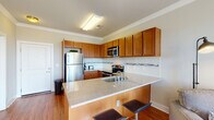 Located along North Third Street in Wilmington, North Carolina, this single-floor unit offers a well-designed layout that balances functionality and comfort. The kitchen serves as a central highlight, featuring warm-toned wood cabinetry extending to the ceiling, stainless steel appliances including a refrigerator, electric range, and built-in microwave, and a tile backsplash with a mosaic accent strip. A peninsula with a granite-style countertop and built-in sink provides additional prep space and doubles as a casual dining area with bar stool seating. Hardwood flooring runs throughout the main living areas, adding warmth and continuity to the space.

The bedroom is carpeted and generously sized, receiving ample natural light through double windows with blinds. A ceiling fan adds practicality, and a walk-in closet with wire shelving provides organized storage. The bathroom features large-format tile flooring, wood cabinetry with a granite-topped vanity, a wide mirror, and a shower with a decorative curtain. The overall ambiance throughout the unit is clean and contemporary, with neutral tones and crown molding detailing lending a polished, cohesive finish.