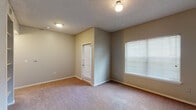 This single-floor unit offers a practical and well-organized layout designed for comfortable everyday living. The entryway opens into a carpeted living area bathed in natural light from a window fitted with blinds. A pass-through opening in the wall connects the living space to the kitchen, creating an open, communicative feel between the two areas.

The galley-style kitchen is efficiently designed, featuring white cabinetry lining both walls, stone-look countertops, a stainless steel double-basin sink, and white appliances including an electric range, microwave, and refrigerator. Wood-look flooring runs throughout the kitchen, providing a clean contrast to the cabinetry.

The bedrooms continue the carpeted flooring and neutral wall tones, each featuring ceiling fans with integrated lighting and windows that allow natural light to filter in. Louvered closet doors provide storage, and textured ceilings are consistent throughout the unit.

The bathroom is appointed with wood-look flooring, a granite-look vanity countertop, white cabinetry for overhead storage, a mirror, and a full tiled tub-and-shower combination. The overall ambiance of the unit is neutral and move-in ready, with a clean, functional aesthetic throughout.