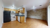 Located at 545 Lowell Ave in Cincinnati's Clifton neighborhood, this one-bedroom, one-bathroom unit offers a well-organized layout across a single floor. Warm hardwood-style flooring runs throughout, unifying the space with a clean, cohesive look.

The open-concept kitchen and living area serves as the heart of the unit. The kitchen features honey-toned wood cabinetry, dark countertops, and white appliances including a range, microwave, and dishwasher, alongside a black refrigerator. A striking exposed brick accent wall borders the living area, adding texture and character to the otherwise neutral, light-gray palette.

The living room is generously proportioned, benefiting from natural light and sliding glass doors that open onto a private balcony with outdoor views of surrounding greenery. A wall-mounted A/C unit and recessed lighting provide added comfort and ambiance.

The bedroom is a comfortable, well-lit room with a window overlooking the exterior and a sliding-door closet with built-in shelving and hanging rods for ample storage. The bathroom features full-height beige tile surrounding a soaking tub and is brightened by a window above.

A dedicated closet and hallway round out the practical layout, making this a functional and inviting urban residence.