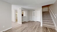 This two-story home offers a practical and well-maintained layout spread across two levels. The main floor welcomes you through a tiled entryway that transitions into durable wood-look laminate flooring, which extends throughout the living areas. The open living room is bright and spacious, featuring neutral warm-beige walls, a textured ceiling, and a carpeted staircase with a white railing leading to the upper level. Closet storage is conveniently accessible near the entry. The kitchen is efficiently designed with white shaker-style cabinetry, light-toned countertops, a pass-through window to the living area, black appliances including a range and dishwasher, and tile flooring. A bathroom on the main floor features a white vanity with under-cabinet storage, a large mirror with overhead lighting, and tile flooring, while an additional half-bath includes decorative diamond-shaped mirrors. Upstairs, the bedrooms are finished with plush carpet and natural light from windows, providing a comfortable retreat. A full bath upstairs features a tub-shower combo with clean white tile surrounds. Throughout, the home maintains a consistent neutral palette, creating a bright and cohesive atmosphere that is move-in ready.