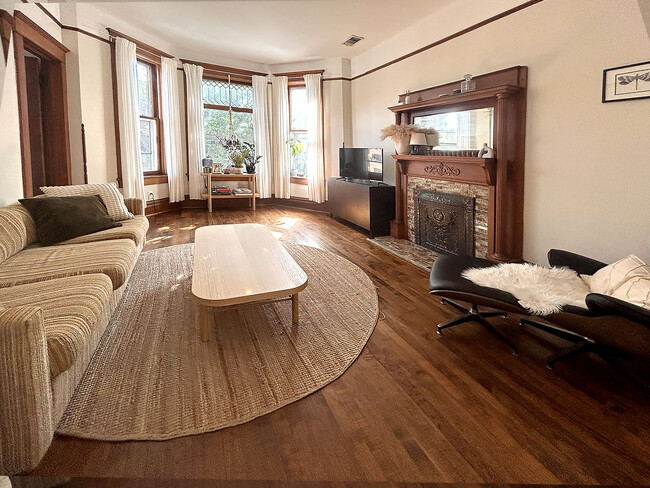 living room has bay window with leaded glass, decorative mantle and high ceilings - 952 N Hoyne Ave