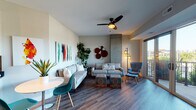 Located at 1700 Marinas Edge Way in Louisville, Kentucky, this single-floor residence offers a thoughtfully designed, open-concept layout with modern finishes throughout. The living area features rich hardwood-style flooring, a ceiling fan, and large sliding glass doors that open onto a private balcony, flooding the space with natural light and offering pleasant outdoor views of the surrounding greenery. A striking exposed concrete column serves as a distinctive architectural accent in the living room.

The kitchen is well-appointed with white cabinetry, dark stone countertops, stainless steel appliances including a French door refrigerator, a central island with a statement stone surface, a stainless overhead range hood, and track lighting overhead. A dedicated dining area sits adjacent to the kitchen for seamless entertaining.

The bedroom is generously proportioned with plush carpeting, a ceiling fan, and a window providing natural light and outdoor views. The bathroom includes a glass-enclosed walk-in shower with clean, contemporary fixtures and wood-look tile flooring. An in-unit laundry area accommodates a full-size washer and dryer alongside wire shelving for added storage. This residence combines contemporary design with practical amenities in a well-appointed, cohesive living environment.
