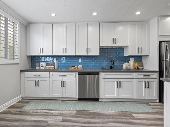 Blue tiled kitchen with stainless steel dishwasher and fixtures. - Hi Point Townhomes