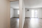Located at 240 Prospect Ave in Hackensack, NJ, this 1-bedroom, 1-bathroom unit offers a thoughtfully designed single-floor layout that maximizes every square foot. Light wood-style luxury vinyl flooring runs throughout the space, lending a clean, contemporary feel to each room. The open living area is bright and airy, featuring sliding glass doors that invite natural light and provide access to the outdoors, complemented by baseboard heating and a wall-mounted A/C unit for year-round comfort. The bedroom is generously sized, offering a wall-to-wall sliding-door closet with built-in shelving and a window that fills the room with natural light. A hallway connects the main living areas and leads to the full bathroom, which showcases marble-style floor-to-ceiling tile surrounding a soaking tub and shower, paired with a grey shaker-style vanity and crisp white countertop. The galley kitchen is efficiently arranged with grey shaker cabinetry, white quartz countertops, stainless steel appliances including a refrigerator, electric range, and dishwasher, and a stainless undermount sink. Two hallways complete the layout, providing practical transitional space throughout the unit.