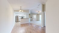 This single-floor, 3-bedroom, 2-bathroom residence offers a practical and comfortable layout designed for everyday living. The open-concept kitchen and living area serves as the heart of the home, where light wood-style flooring flows seamlessly underfoot. The kitchen is outfitted with crisp white cabinetry, granite-style countertops, stainless steel appliances including a refrigerator and electric range, and a peninsula that doubles as a breakfast bar. A skylight above the kitchen adds an extra touch of natural brightness. An elegant chandelier marks the transition into the dining area, while the adjoining living room features a ceiling fan and sliding glass doors that open onto a private balcony, flooding the space with natural light. The bedrooms are carpeted for comfort, each equipped with ceiling fans and windows that invite natural light. The primary bedroom is generously sized and includes access to outdoor views via a sliding glass door. Both bathrooms are clean and functional, each featuring a full tub-shower combination with white tile surround, wood-style flooring, and bright, neutral finishes. Two hallways provide smooth connectivity throughout the home. The overall palette of soft neutrals and white trim lends the space a fresh, move-in-ready feel.