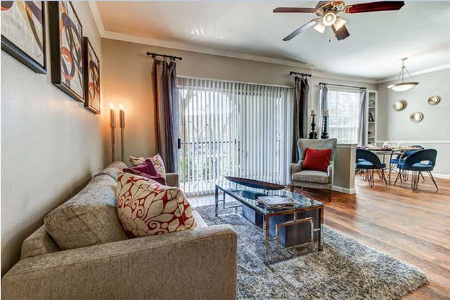 Living room with open dinning and kitchen areas, ceiling fan, balcony access and wood-style floors - Colonnade