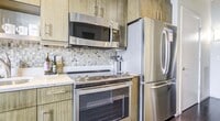 This 560 square foot apartment offers a thoughtful blend of contemporary design and functionality. The open-concept living area seamlessly integrates with a modern kitchen, characterized by vibrant yellow cabinetry, stainless steel appliances, and a stylish mosaic tile backsplash. The kitchen's L-shaped layout maximizes space efficiency, featuring a breakfast bar that doubles as a dining area.

The living room boasts wood-look flooring and large windows that flood the space with natural light, offering impressive city views. A sliding glass door leads to a private balcony, perfect for enjoying the urban landscape.

The bedroom, measuring 100 square feet, provides a cozy retreat with ample space for a queen-sized bed and essential furniture. The bathroom is well-appointed with a modern vanity, a combination shower/tub, and clean, white tiling.

Throughout the apartment, track lighting and recessed fixtures provide adjustable illumination. A closet offers additional storage space, while the apartment's single-floor layout ensures easy navigation. The property's urban setting is evident through the windows, showcasing neighboring high-rises and the vibrant cityscape beyond.